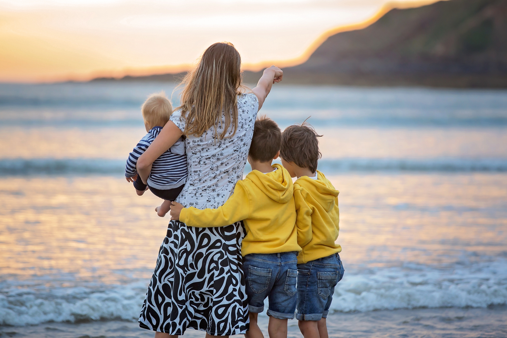 Family showing a mother with 3 children staring out at a seaside sunset